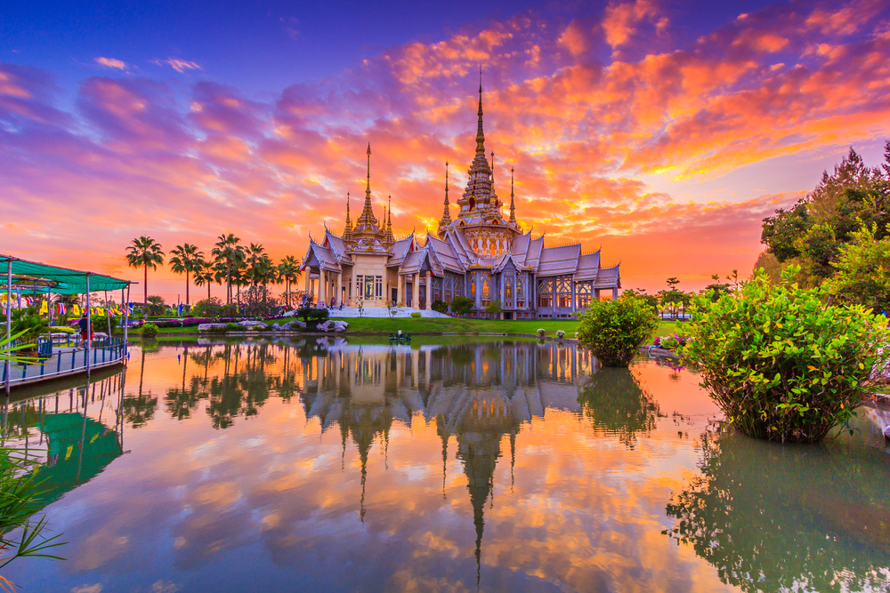 pagoda in thailand with sunset and water reflection over a lake