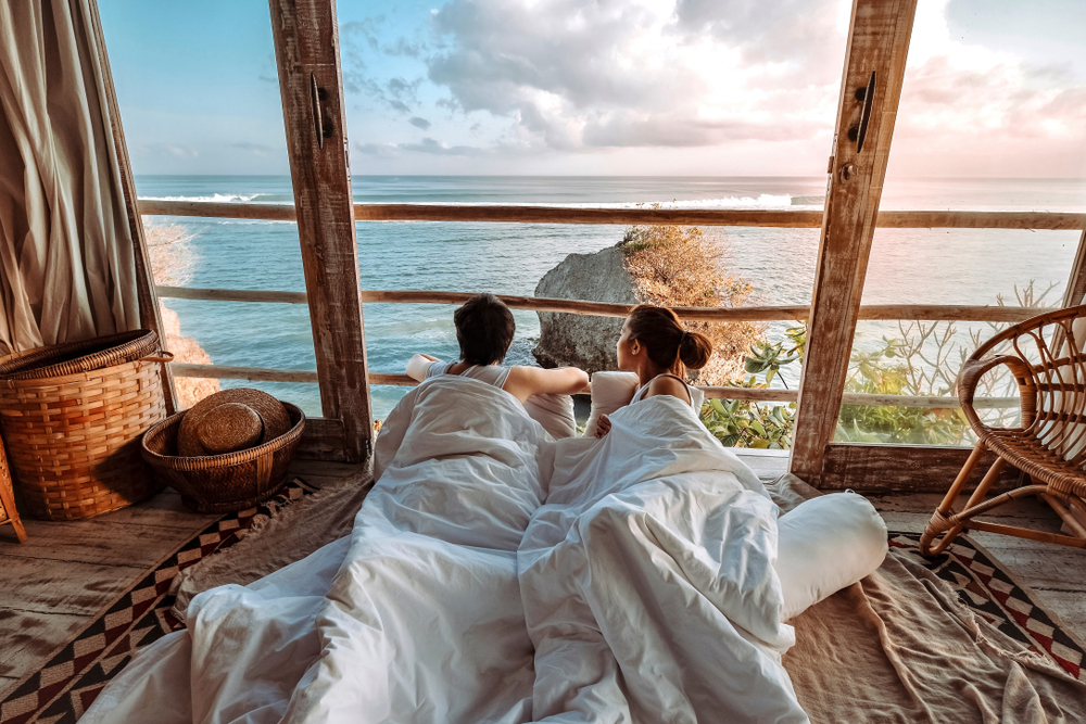 couple waking up in bed to an amazing sea view over the mountains