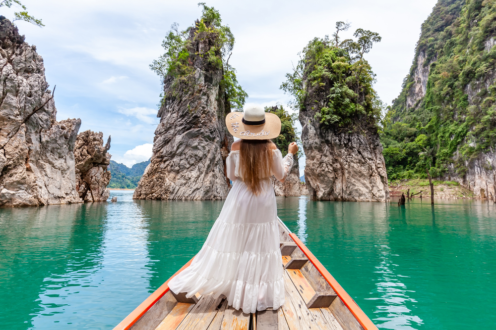 girl in white long dress stands at the edge of the boat in Thailand