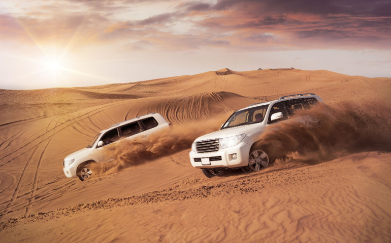 Vehicles bashing side to side through the desert dunes.