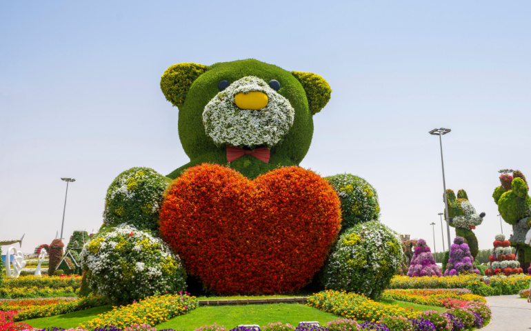 Big teddy bear covered with flowers with heart in his hands at Dubai Miracle Garden