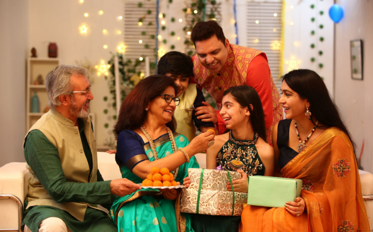 Family enjoying sweets and exchanging gifts on Diwali