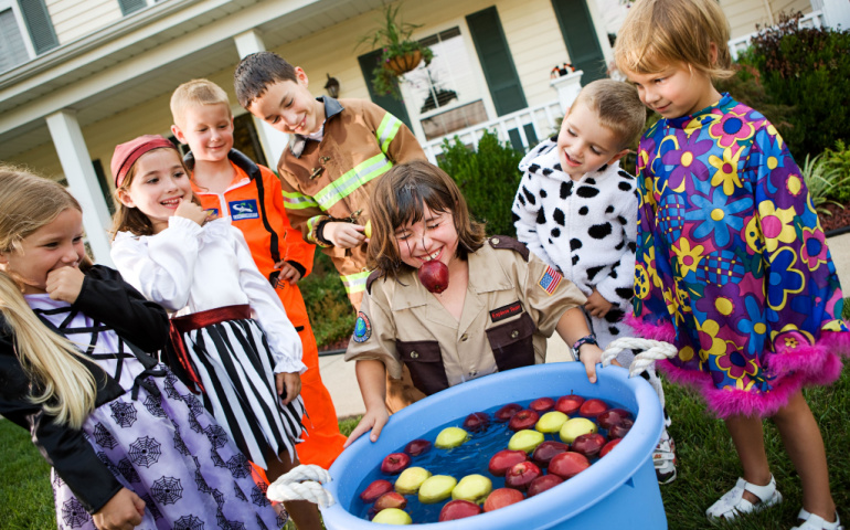 Children in costumes bobbing for apples on Halloween