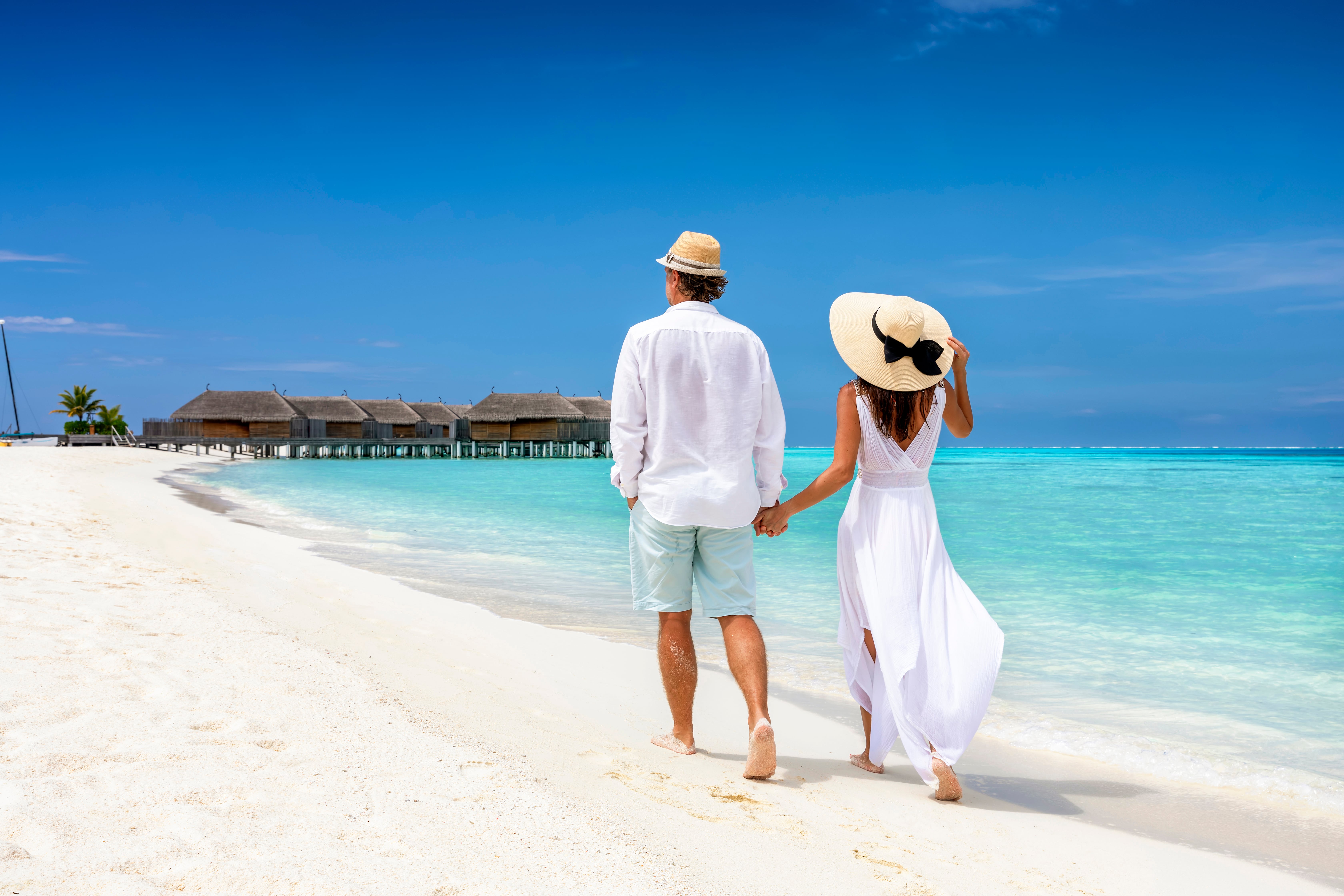 Romantic couple walking on the white sandy beach in the Maldives