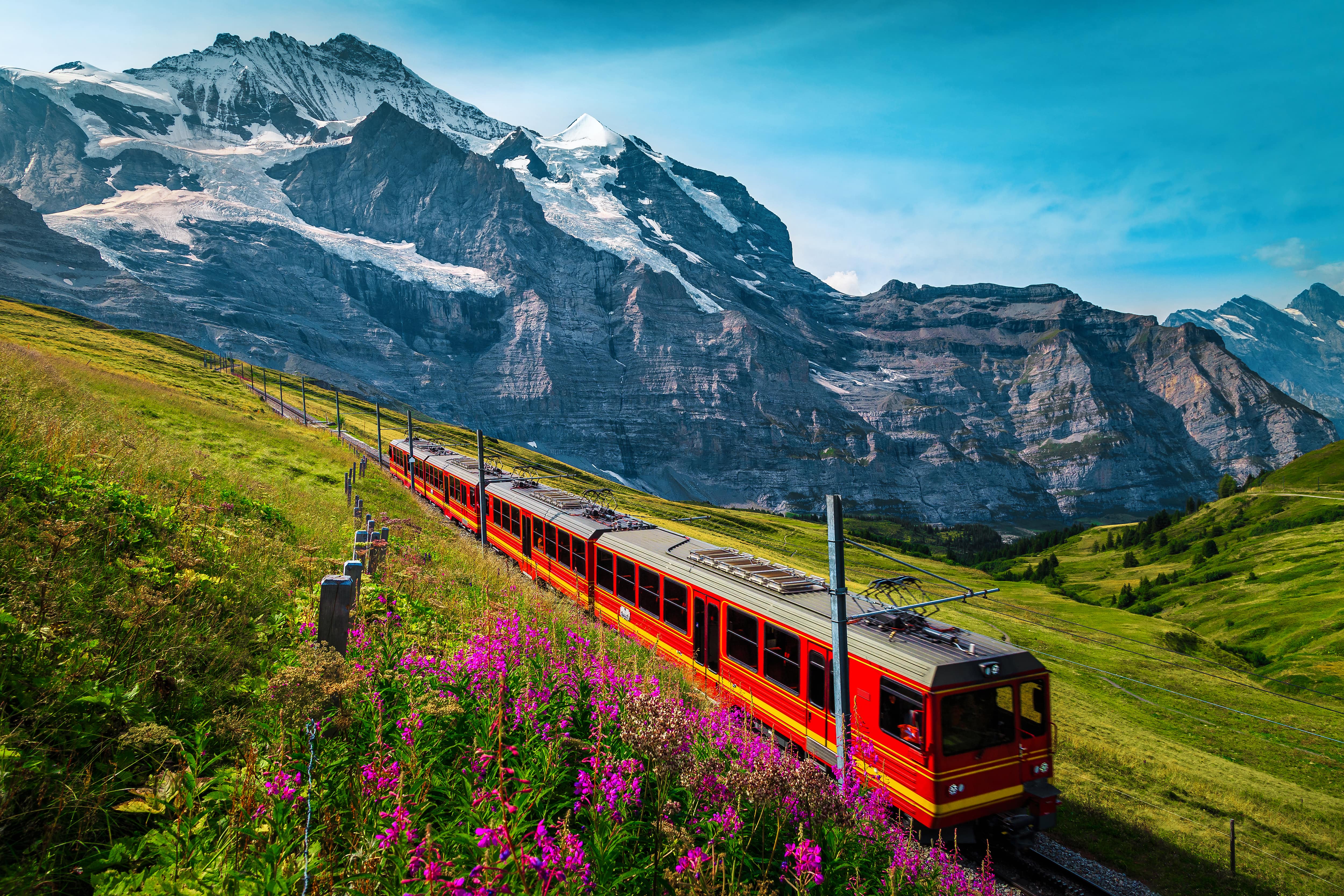 The red swiss train traversing through the lush green mountains of switzerland