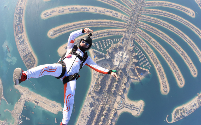 People lies on beach Dubai Palm in free fall sky jump 