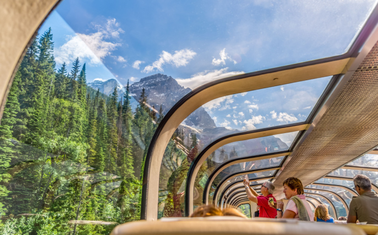Rocky Mountaineer train traveling through the Rocky Mountains with luxury dining on board.