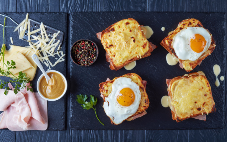 Croque Monsieur and Croque Madame with slices of boiled ham, melted emmental cheese and fried sunny side up egg