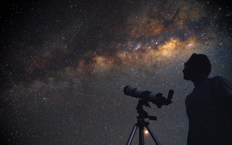 Astronomer with a telescope watching the stars and Moon