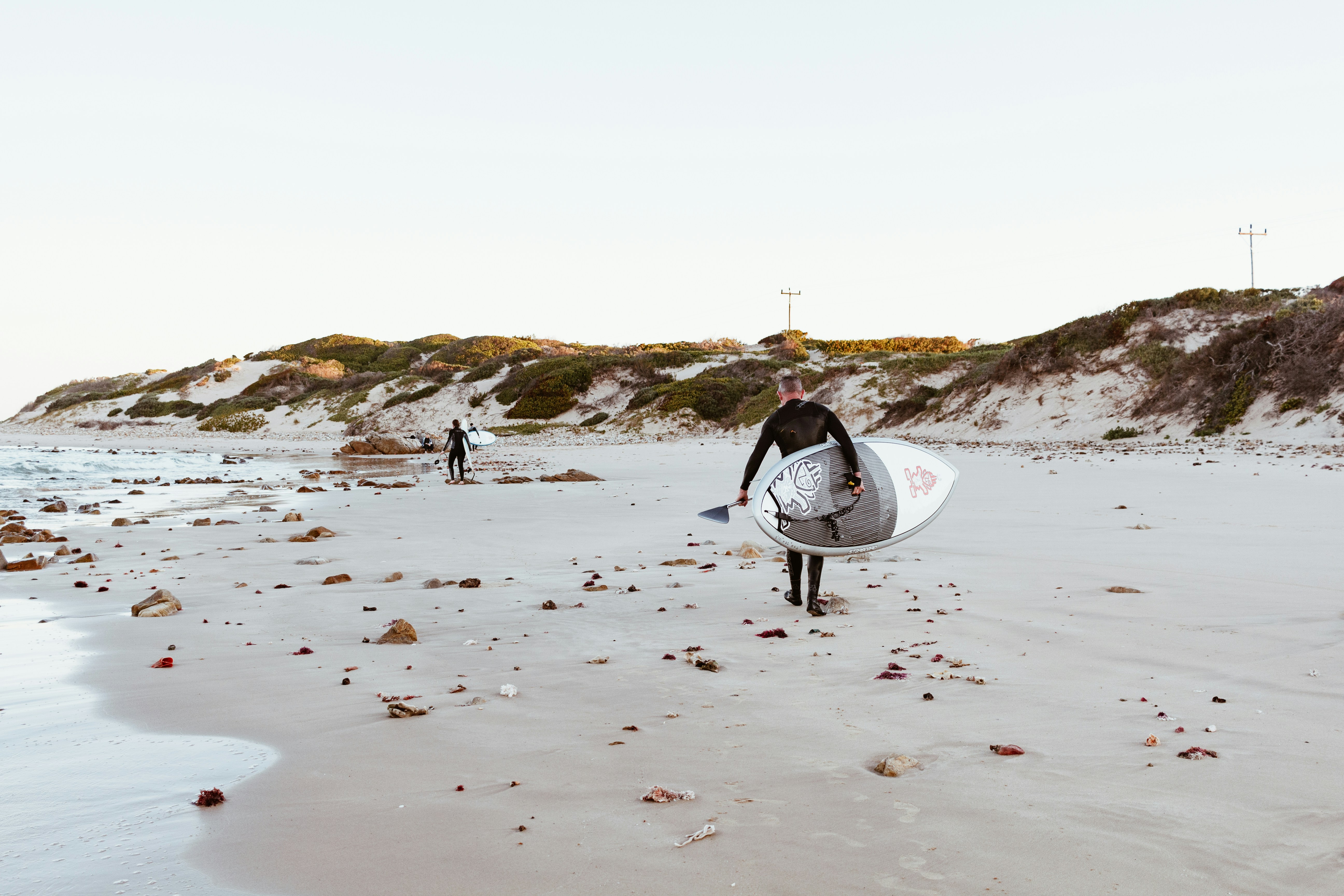 A man with his skateboard on the beach