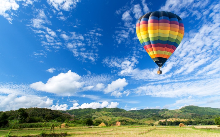 Hot air balloon over the field with blue sky. 