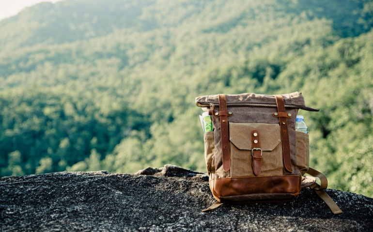 Vintage bagpack put on peak of mountain.
