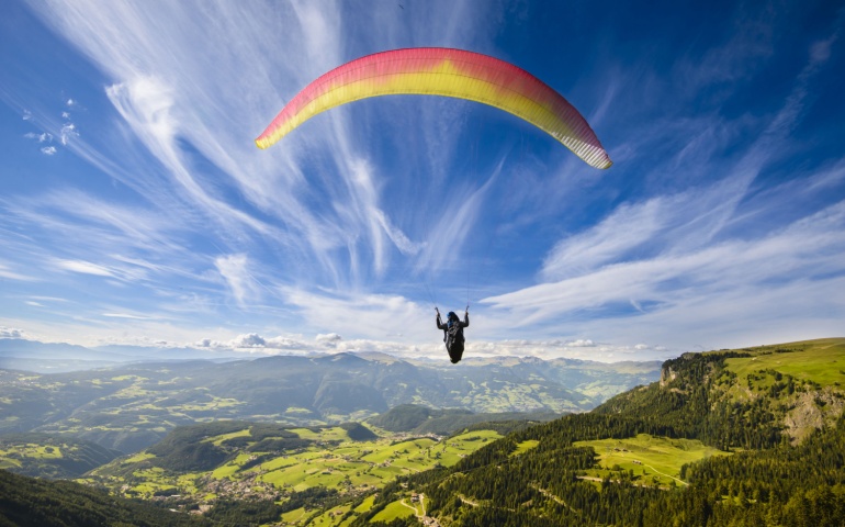 Paraglider flying over mountains in summer day. 