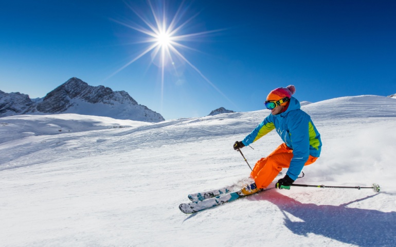 Skier skiing downhill during sunny day in high mountains. 
