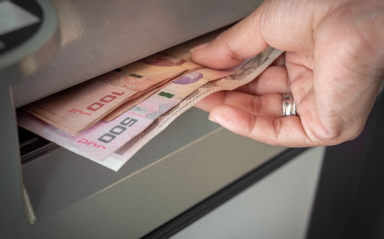 Withdrawing Thai Baht from an ATM machine.