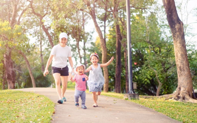 Mother and children running in the park on a bright day.