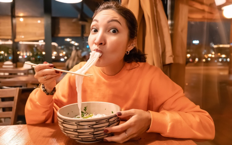 Woman eating Vietnamese Noodle Soup with chopsticks