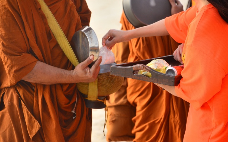 Handing offerings to the Buddhist Monks with the right hand