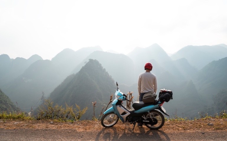 A backpacker enjoys the views on a motorcycle trip through the HA GIANG loop