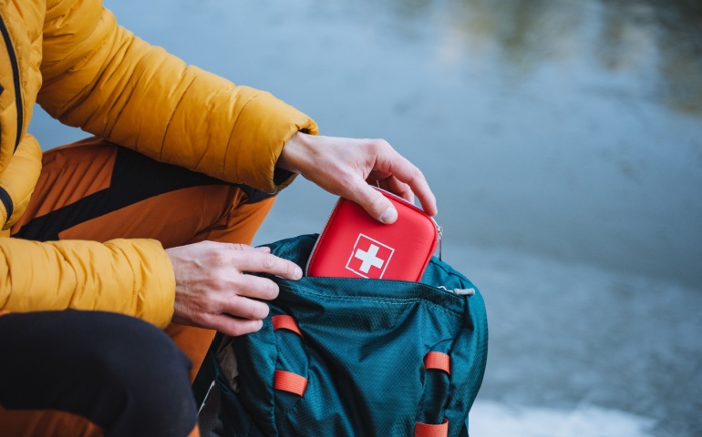 A man packing a first-aid kit in his backpack