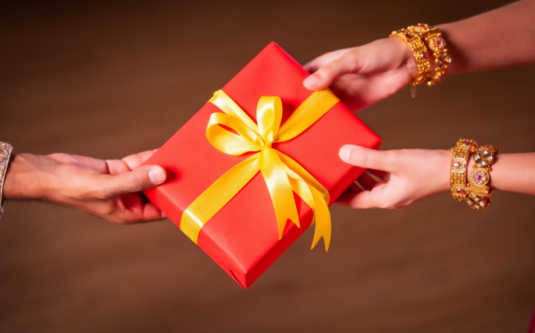 A gift wrapped in red paper with a golden ribbon.