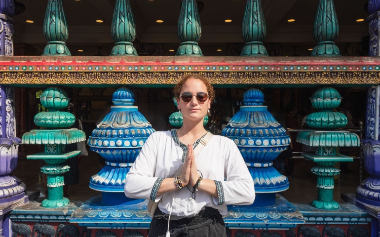 Woman tourist doing the namaste pose in front of Batu Caves