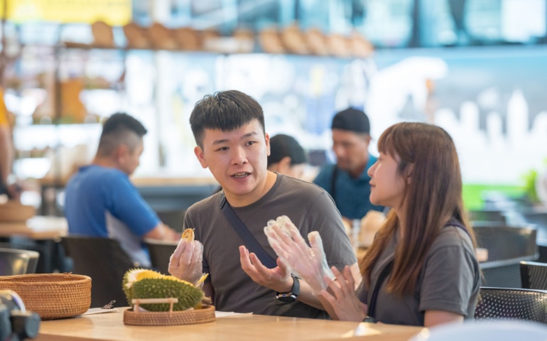 Two people eating durian in public