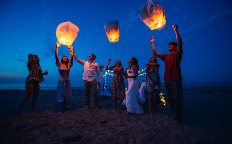 Group of friends leaving sky lanterns on the beach 